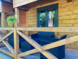 weranda drewnianej kabiny z niebieskimi krzesłami w obiekcie Osada Międzywodzie w mieście Międzywodzie