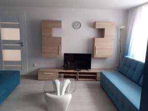 uma sala de estar com um sofá azul e uma televisão em Na Spokojnie em Jastarnia