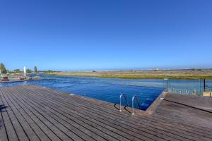 a swimming pool on a wooden deck next to the beach at Ken Blacklock in Fuzeta