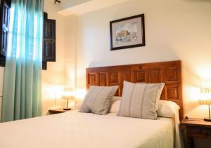 1 dormitorio con 1 cama con sábanas blancas y 2 lámparas en El Balcón del Rey, en Ruidera