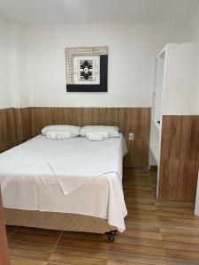 Schlafzimmer mit einem Bett mit weißer Bettwäsche in der Unterkunft Zaca’s House in Vila Velha