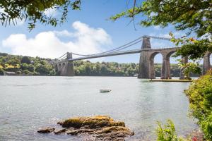 a bridge over a river with a boat in the water at The Art Deco House in Menai Bridge +4 photos