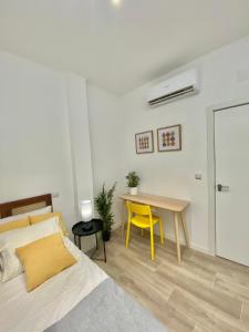 1 dormitorio con cama, mesa y silla amarilla en Mejorana Apartament, en Madrid