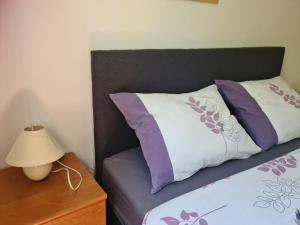 een bed met paarse en witte kussens en een lamp bij Apartmani Junto in Preko