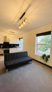 a living room with a black couch and a kitchen at YO ROOM! Apartments- Next to City Centre Apartment - With Free Parking in Leicester