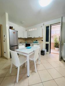 La cuisine est équipée d'une table et de chaises blanches ainsi que d'un réfrigérateur. dans l'établissement Nerissa Holiday Home, à Gallipoli