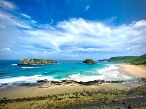 una vista aerea di una spiaggia con rocce nell'oceano di Hospedaria Casa dos Gêmeos- Fernando de Noronha-PE a Fernando de Noronha