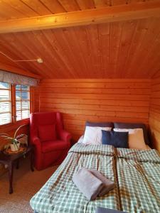 um quarto com uma cama e uma cadeira vermelha em Timber cottages with jacuzzi and sauna near lake Vänern em Karlstad