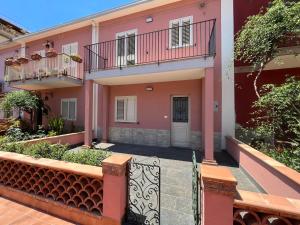 une maison rose avec une porte devant elle dans l'établissement La Ginestra, à Giardini Naxos