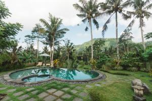 a pool in a garden with palm trees at Griya Valud in Sidemen