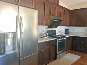 uma cozinha com armários de madeira e um frigorífico de aço inoxidável em @ Marbella Lane - 3BR Elegant House Laundry + P em Newark