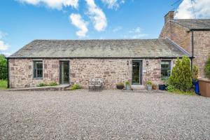 una antigua casa de piedra con una entrada de grava en The Garden Cottage, en Doune