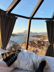 a bed in a room with a view of the ocean at Aurora Hut by InukTravel in Nuuk