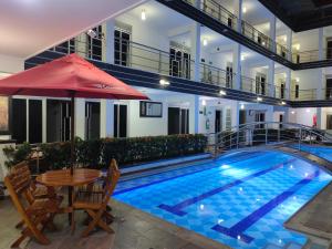a swimming pool with a table and an umbrella at Confort Plaza Hotel in Villavicencio