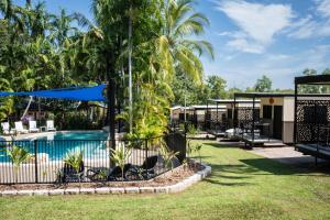 a resort with a swimming pool and palm trees at Oasis Tourist Park in Palmerston