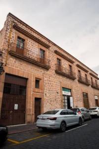 due auto parcheggiate di fronte a un edificio di mattoni di Apartamento princesa Rosaura a Morelia