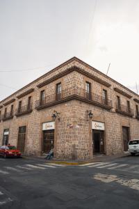 un edificio in mattoni con macchine parcheggiate di fronte di Apartamento princesa Rosaura a Morelia