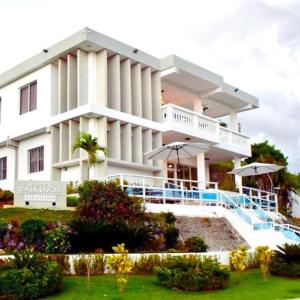 a large white building with umbrellas in front of it at Casa Docia Hotel in Santa Bárbara de Samaná