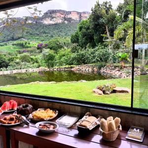 a table with food and a window with a view at Pousada Raposa in Ibicoara