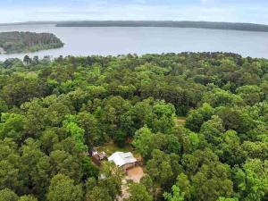 an aerial view of a house in the woods next to a lake at Cozy Getaway at Lake O' the Pines in Ore City