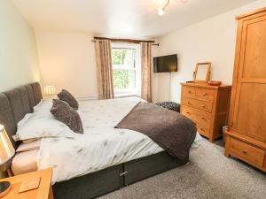 a bedroom with a bed and a dresser and a window at 27 Bongate in Appleby