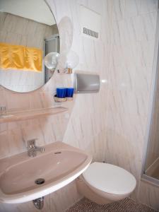ein Badezimmer mit einem Waschbecken, einem WC und einem Spiegel in der Unterkunft Hotel-Restaurant Köhler in Stuttgart