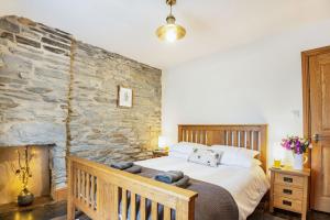 um quarto com uma cama e uma parede de pedra em Garreg Ddu em Blaenau-Ffestiniog