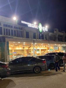 una tienda con autos estacionados frente a ella por la noche en 12PAX 2BR near USM S PICE ARENA AIRPORT, en Bayan Lepas