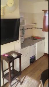 una pequeña cocina con mesa y TV en la pared en Monoambientes Arizu en Godoy Cruz