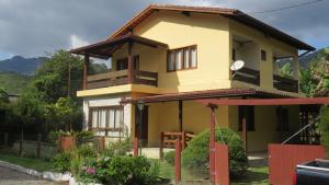 una casa amarilla con una valla roja delante de ella en 4 Quartos a 500m Centro - Sauna, Piscina, Fogão a Lenha, Churrasqueira - ACESSO PRIVATIVO AO AO RIO - Ideal para famílias en Nova Friburgo