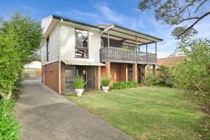 a large house with a balcony and a yard at Sputnik Beach House by Experience Jervis Bay in Vincentia