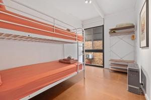a bedroom with two bunk beds and a window at Sputnik Beach House by Experience Jervis Bay in Vincentia
