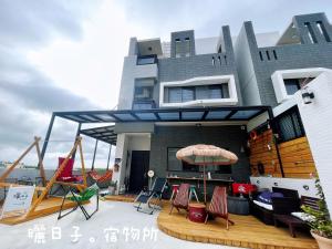 una casa con una terrazza con sedie e un'altalena di 曬日子宿物所Sundays BnB 包棟民宿 a Huxi
