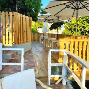 Casa Docia Hotel في سانتا باربرا دو سامانا: سطح خشبي مع طاولات ومظلة