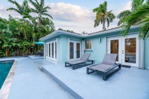 a blue house with two chairs and a swimming pool at Luxurious Fort Lauderdale Pool Home in Fort Lauderdale