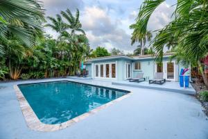 a swimming pool in front of a house with palm trees at Luxurious Fort Lauderdale Pool Home in Fort Lauderdale