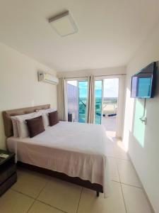 um quarto com uma grande cama branca e uma televisão em Arraial do Cabo. Cobertura Espetacular c Vista Mar em Arraial do Cabo