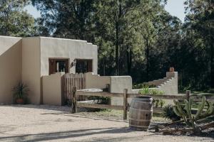 a small house with a fence and a barrel at Casa La Vina Pokolbin - Romantic Villas with Outdoor Hot Tubs and Fireplaces in Pokolbin