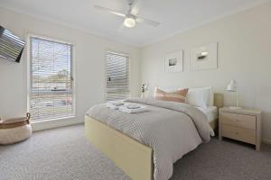 a white bedroom with a bed and a window at Rock Salt by Experience Jervis Bay in Huskisson