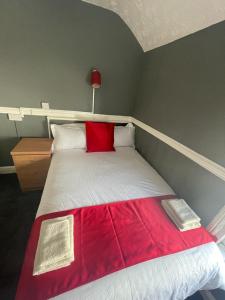 a bed with a red blanket on top of it at KM Central Pier in Blackpool