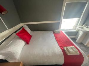 a bedroom with a white bed with red pillows and a sink at KM Central Pier in Blackpool