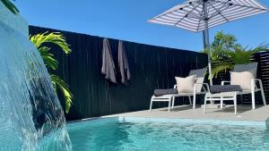 a swimming pool with chairs and an umbrella next to a fence at Bellbry Lodge in Trinity Beach