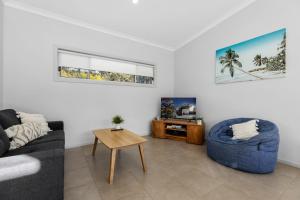 a living room with a couch and a table and a tv at The Oasis of Calm by Experience Jervis Bay in Huskisson