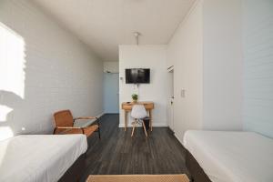 a room with two beds and a desk and a tv at Little Coogee Hotel in Sydney