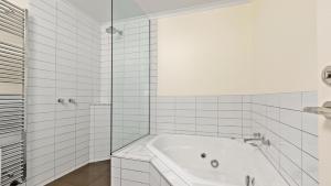uma casa de banho em azulejos brancos com uma banheira e um chuveiro em Lawlers 6 em Mount Hotham