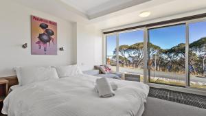 um quarto com uma grande cama branca e janelas grandes em Lawlers 6 em Mount Hotham