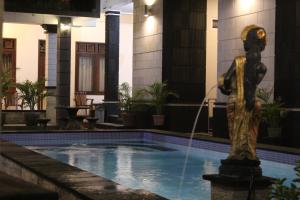 a statue in a pool with a water fountain at New ASTA GRAHA GUESTHOUSE in Jimbaran