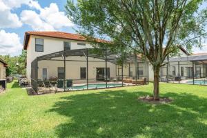 a house with a pool and a tree in the yard at Romantic forest view 5BR Minutes to Disney in Kissimmee
