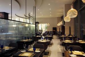 a restaurant with black tables and chairs and chandeliers at LOTTE City Hotel Gimpo Airport in Seoul