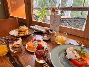 einen Holztisch mit Teller mit Speisen und Orangensaft in der Unterkunft Paperbark Camp in Woollamia